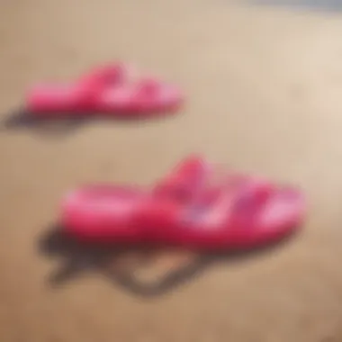 Vibrant hot pink jelly sandals on a sandy beach